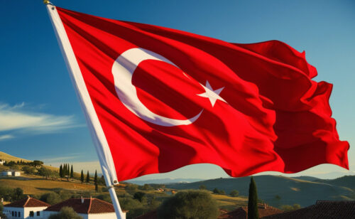 Die Flagge der Türkei weht vor einem idyllischen Landstrich.